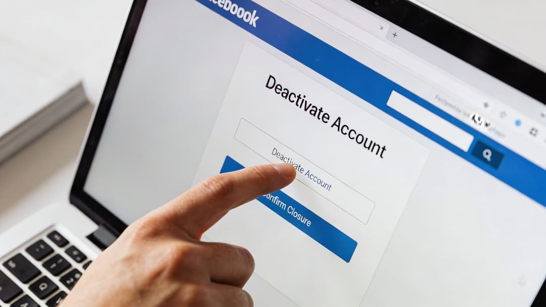A close-up view of a person using their finger to click the Deactivate Account button on a laptop screen.