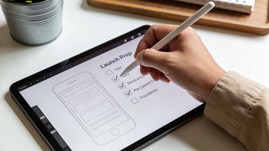A person using a digital pen on a tablet to check off tasks on a launch preparation list.
